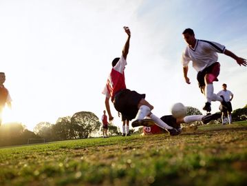 Two men playing soccer intensely on a grassy field.