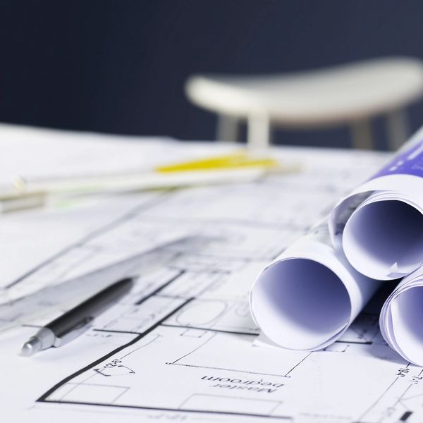 Rolled architectural blueprints and a pen on a table.