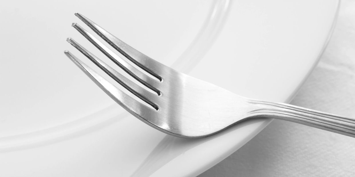 Close-up of a fork resting on a white plate.
