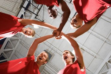 Team of basketball players celebrating with hands together.