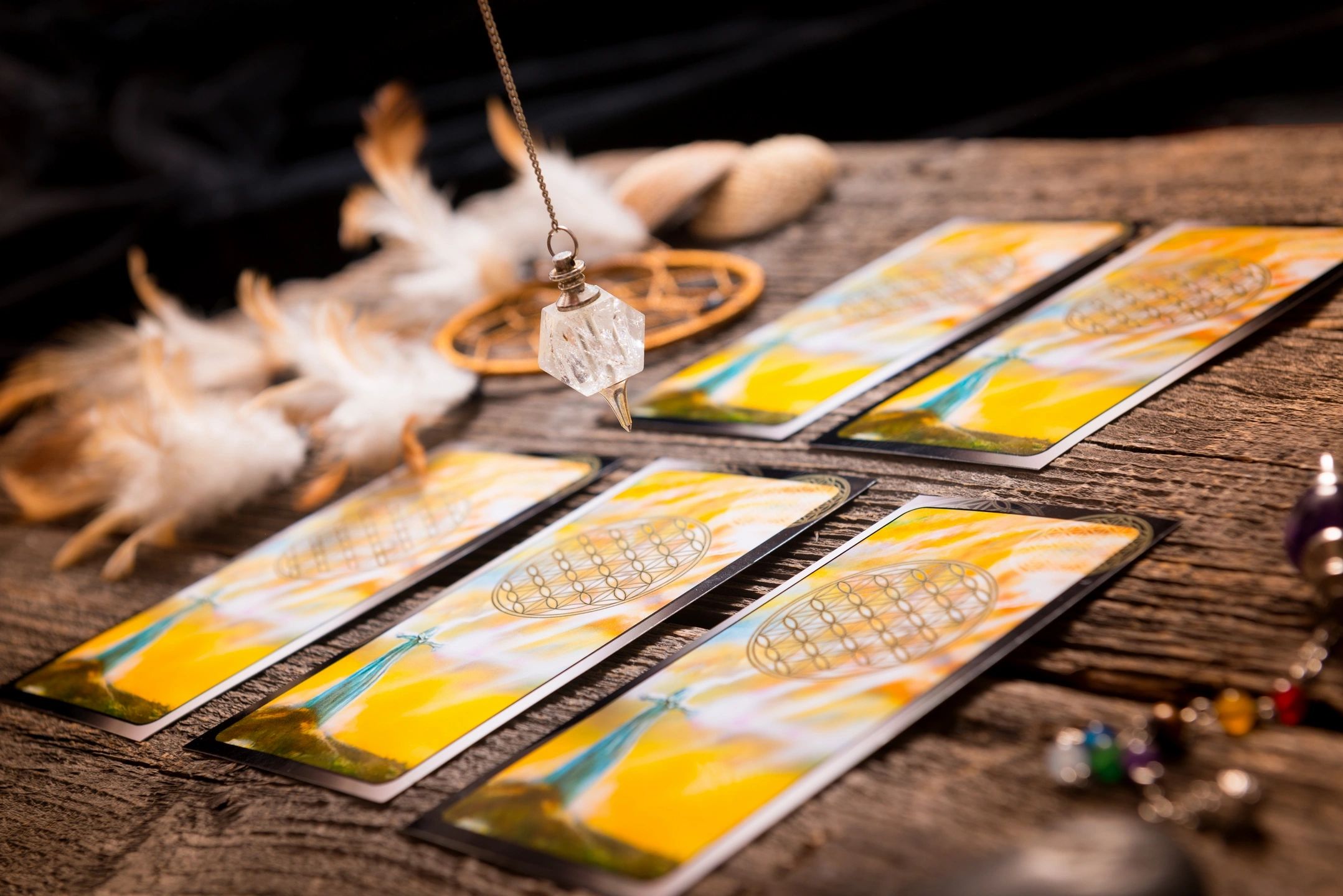 A crystal pendulum above tarot cards laid out on a table 