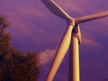 Close-up of a wind turbine against a purple sky.