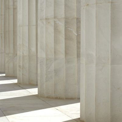Sunlit marble columns casting shadows in a classical architectural setting.