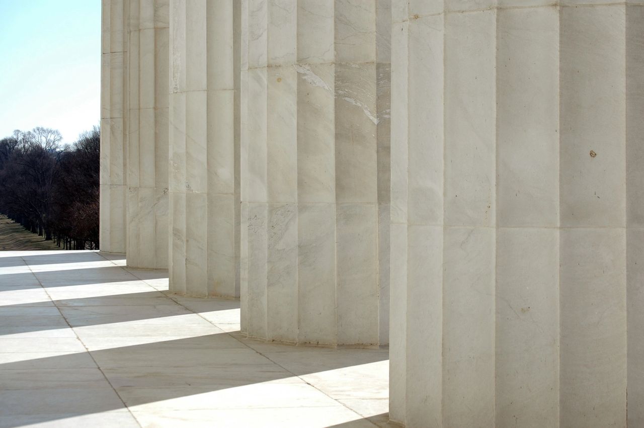 Pillars of building columns, show the shadows they create, along the walkway.