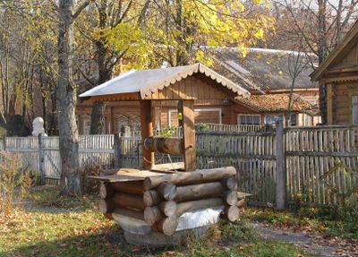 A rustic wooden well in a yard during autumn.