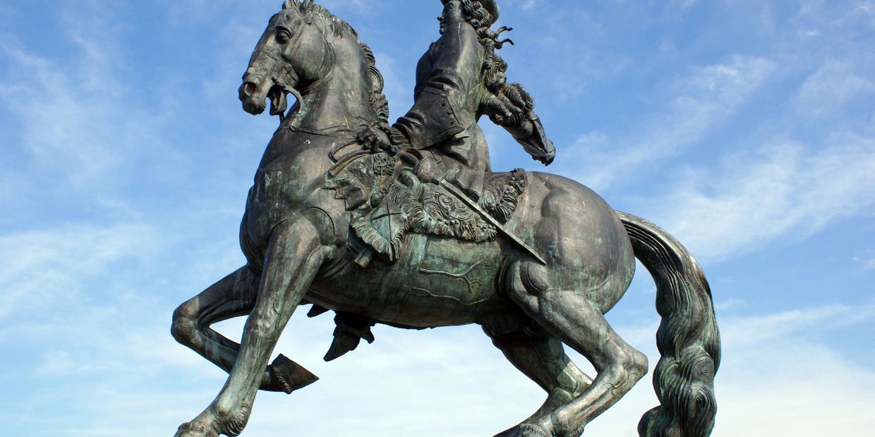 Bronze equestrian statue against a blue sky.