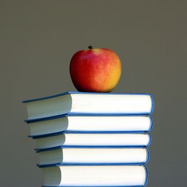 a pile of books with an apple on top