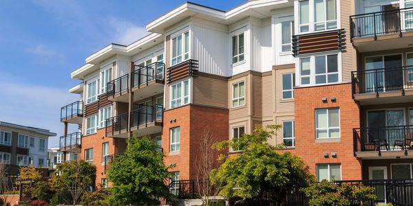 Modern multi-story apartment building with balconies and greenery.