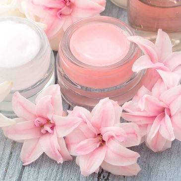 Pink and white creams surrounded by delicate pink flowers on a wooden surface.