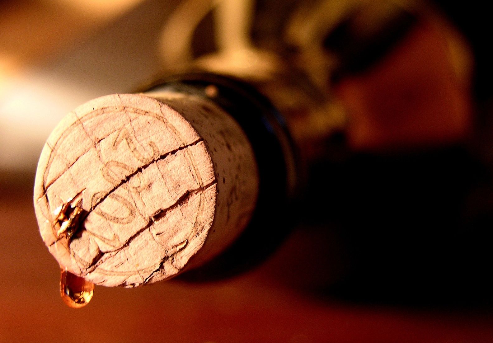 Goutte de vin s'écoulant d'un bouchon de liège sur une bouteille.