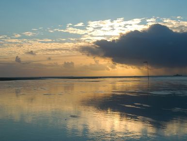 Sunset over water with clouds reflecting.