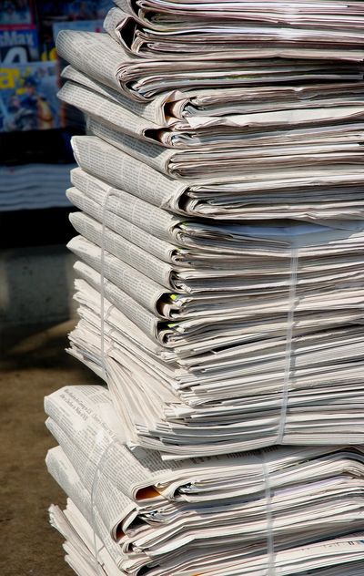 Stack of bundled newspapers tied with string, ready for distribution.