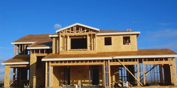 Wooden frame of a house under construction against a blue sky.