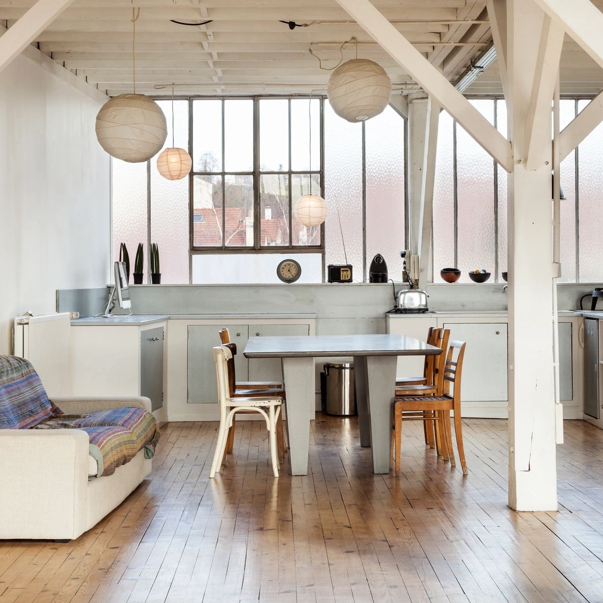 Bright minimalist dining area with wooden chairs and modern kitchen.