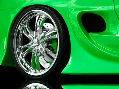 Close-up of a shiny chrome wheel on a bright green sports car.