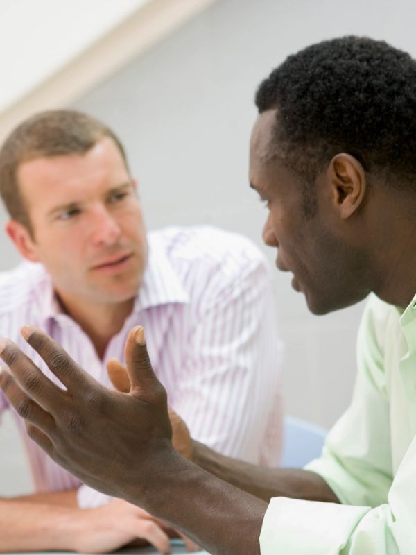 Two men engaged in a serious conversation indoors.