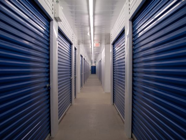 A long hallway lined with blue storage unit doors on both sides.