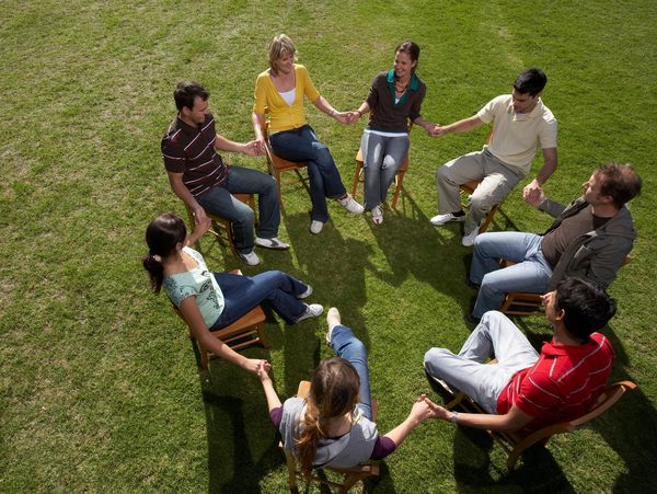 Group of people sitting in a circle holding hands