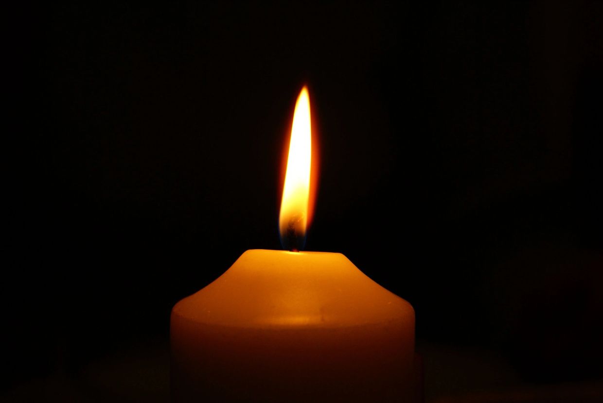image of a single candle burning brightly and illuminating the dark