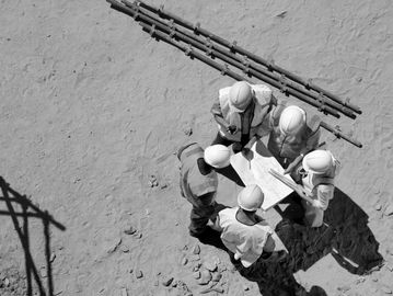 Group of construction managers reviewing building drawings on site