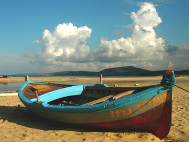 Old wooden boat on a beach with cloudy sky.