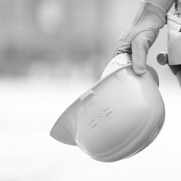 Hand holding a construction helmet with a blurred background.