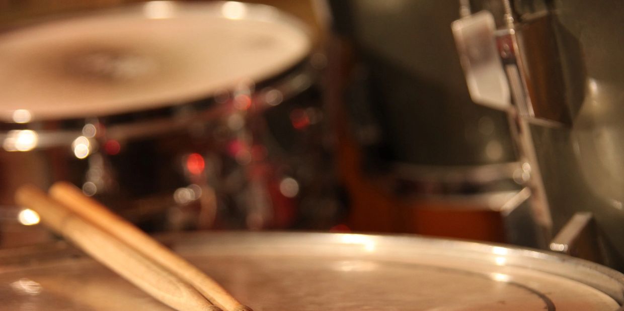 Drumsticks resting on a snare drum with blurred background.