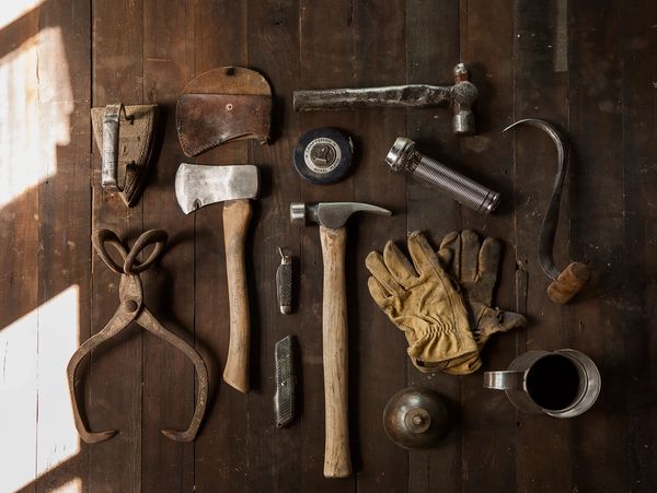 Vintage woodworking tools and gloves arranged on a wooden surface.