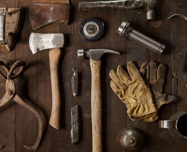 Attrezzi da lavoro vintage disposti su tavola di legno.
