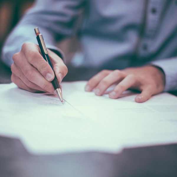 man in button up shirt writing on papers