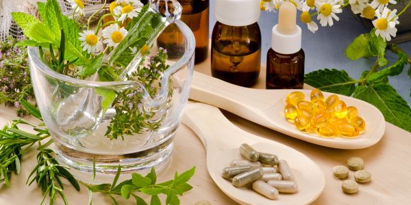 Herbs in a glass cup with vitamins in a Spatula define integrative medicine