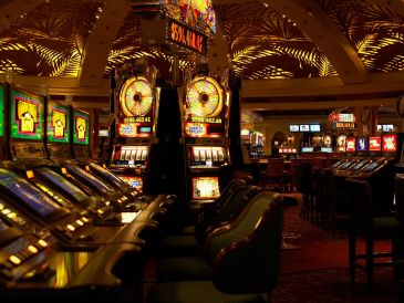 Dimly lit casino slot machines and chairs.