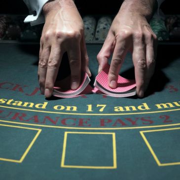 Tangan membagikan kartu di meja blackjack.