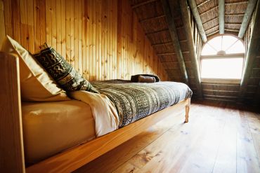 Cozy attic bedroom with wooden walls and a single bed.