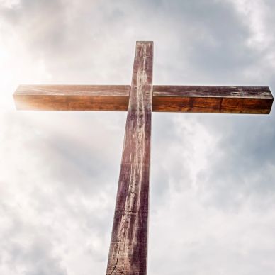 Wooden cross against cloudy sky.