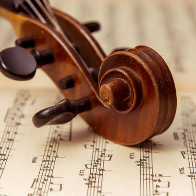Close-up of a violin scroll resting on sheet music.
