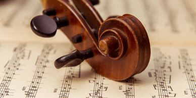 Close-up of a violin scroll resting on sheet music.