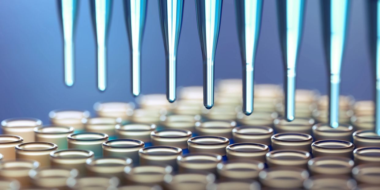 Pipettes dispensing blue liquid into test tubes in a laboratory.