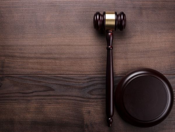 A wooden judge's gavel and sound block on a wooden surface.