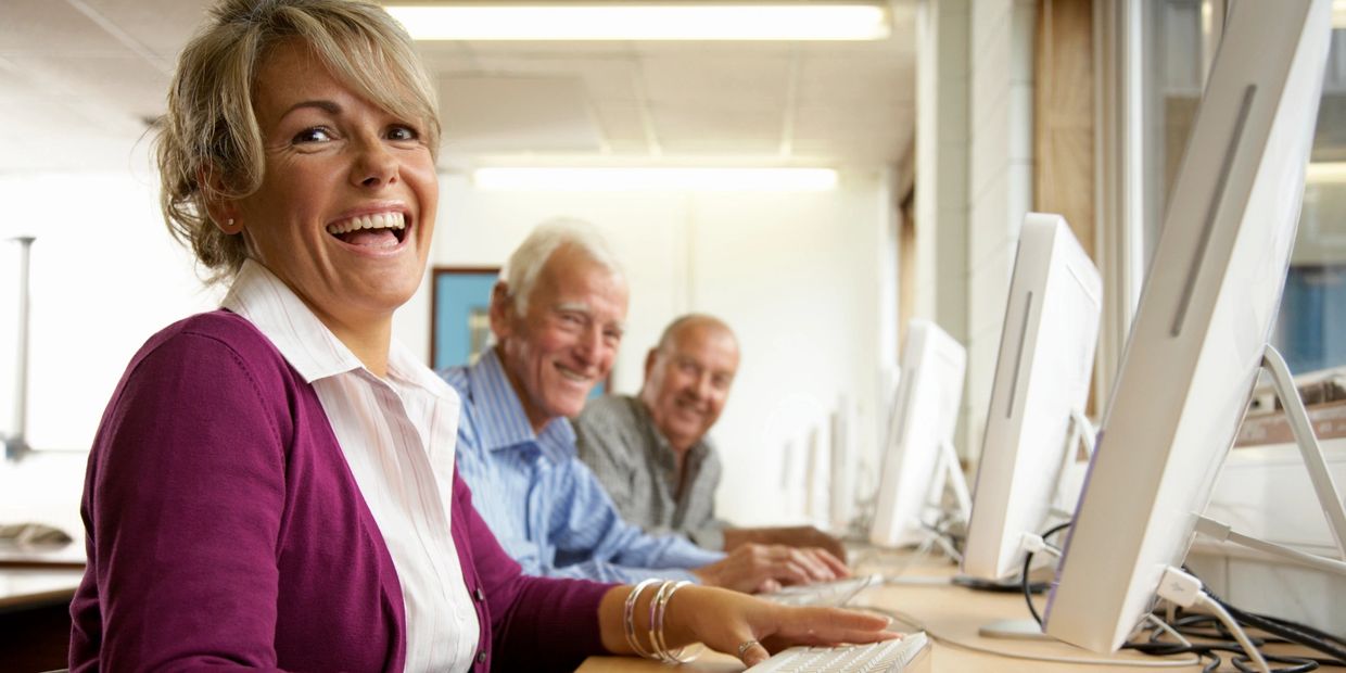 Happy adults working on computers in a bright room.