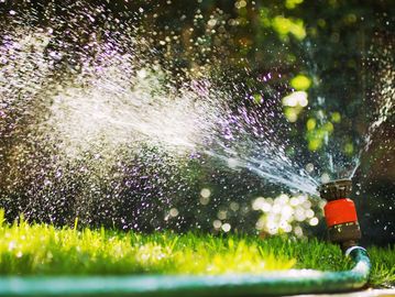A garden sprinkler spraying water on green grass.