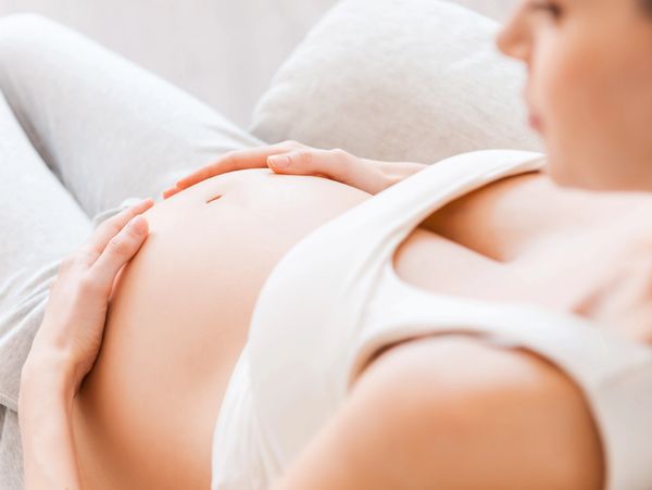 Pregnant woman gently holding her belly, resting peacefully.
