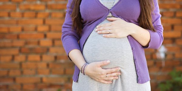 Pregnant woman holding her belly outdoors.