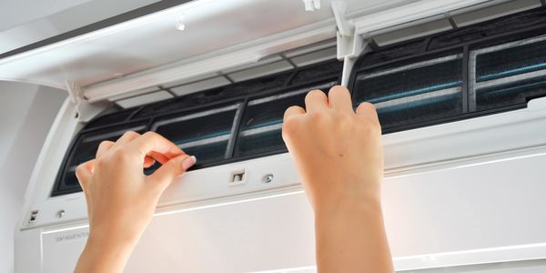 Woman interacting with a wall mounted air conditioning unit.