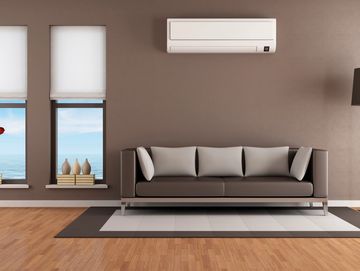 Room with sofa with white air conditioning unit mounted on the wall