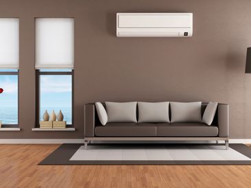 Wall-mounted air conditioner above a modern living room sofa