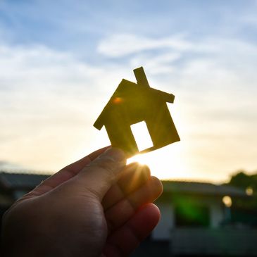 a cut out of a house with a hand holding it towards the sky