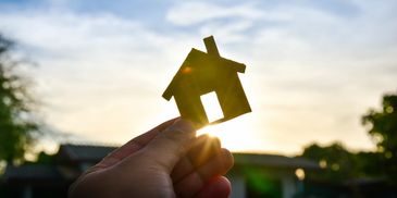 Cut out of a house being held up at sunrise