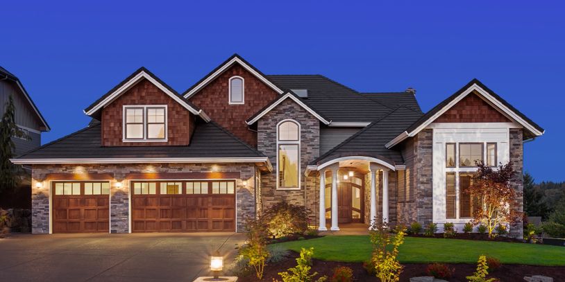 Nice exterior of home built with stone and wood at dusk 