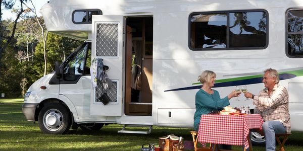 Two people eating outside of their RV enjoying wine